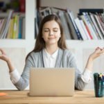 Woman meditating in front of her laptop